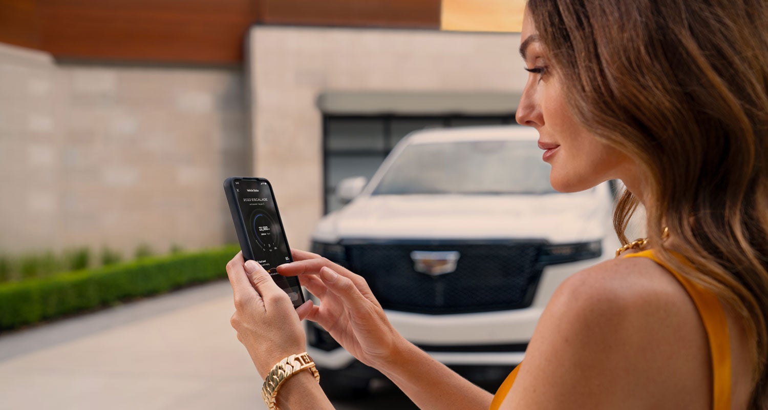 lady checking her mobile with a Cadillac vehicle background | Bridgeton Cadillac in Bridgeton NJ